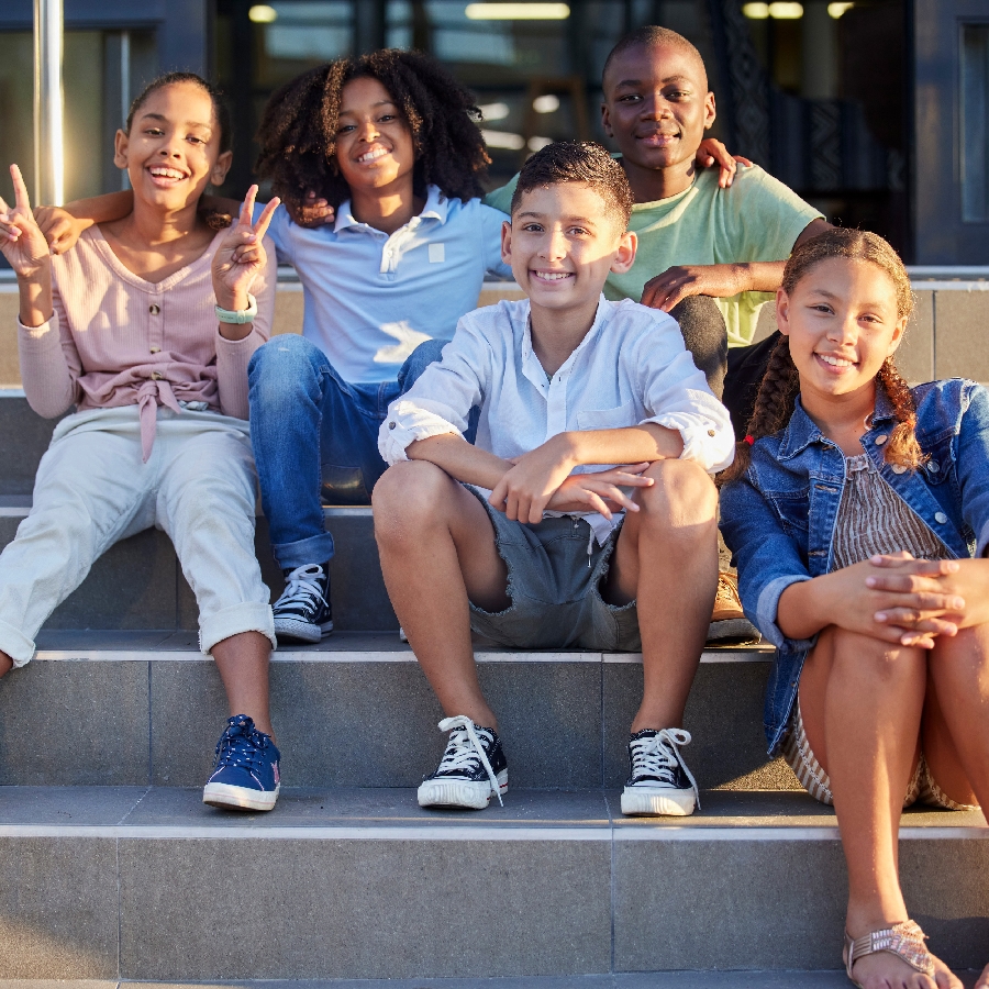 A group of school friends sitting on steps, smiling