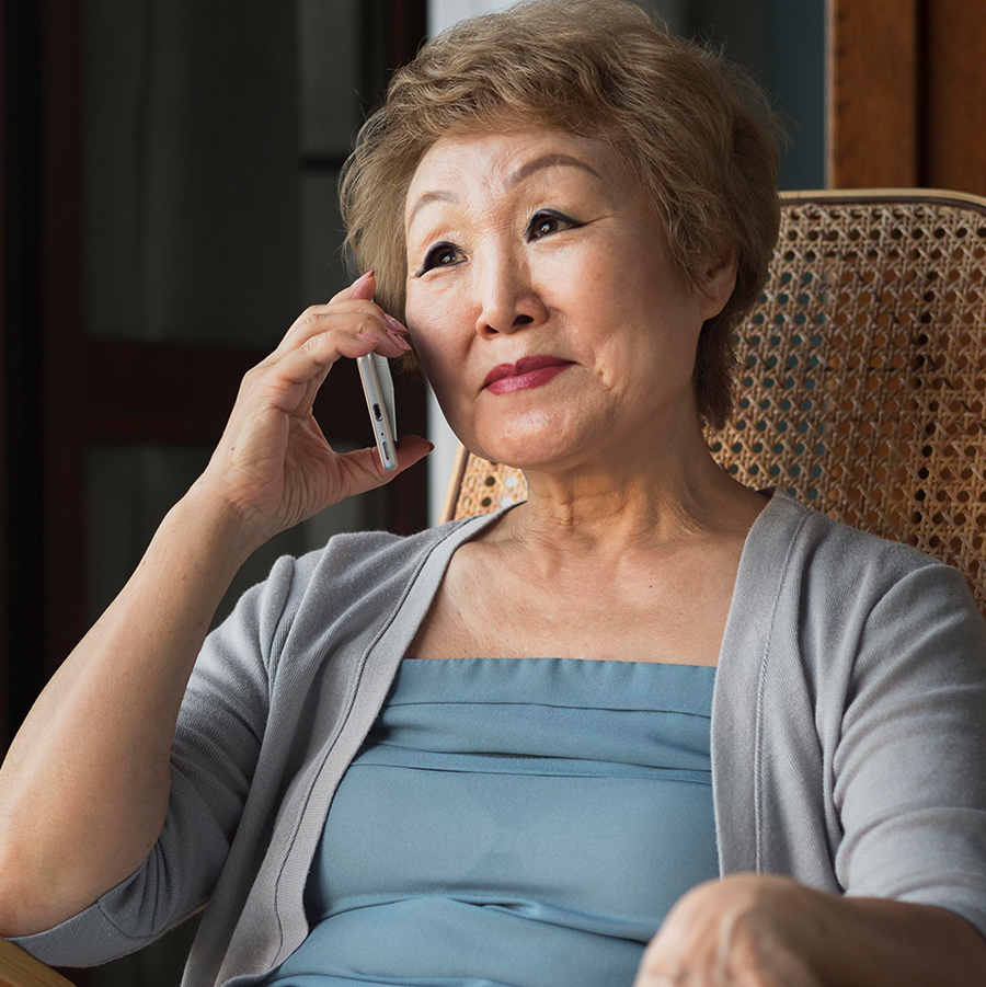 Elderly Asian woman sitting in a chair and talking on a cell phone