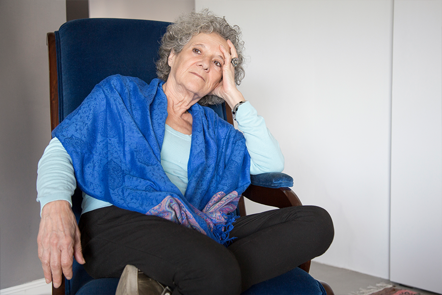 Sad, older woman sitting alone in a corner.